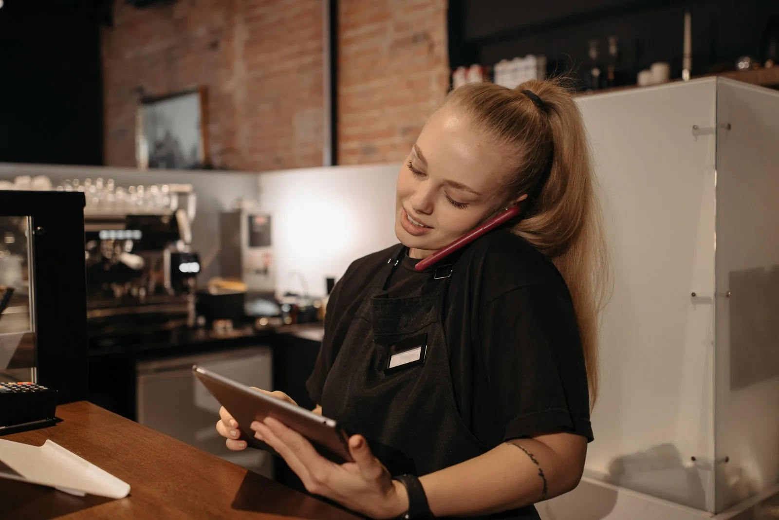 Atendente de restaurante confere pedido de delivery em tablet no balcão